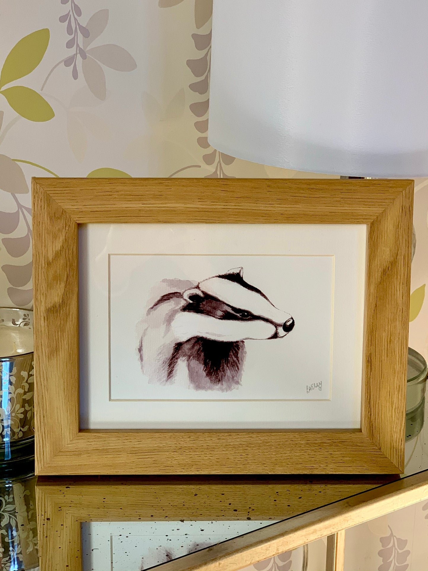 Watercolour young badger painting in grey tones in a oak finish wooden frame with white mount.