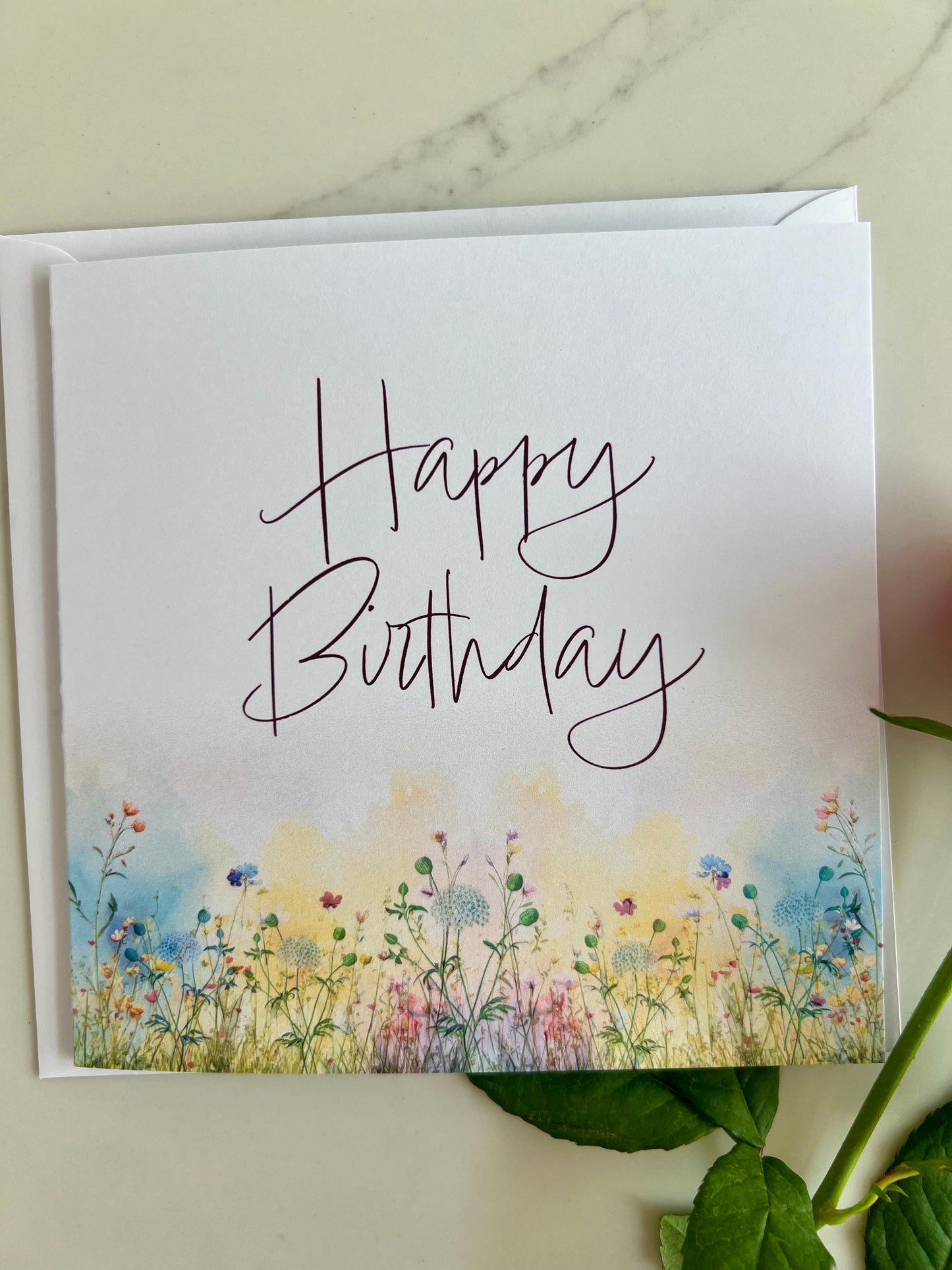Birthday card with 'Happy Birthday' text and floral design on a marble surface.