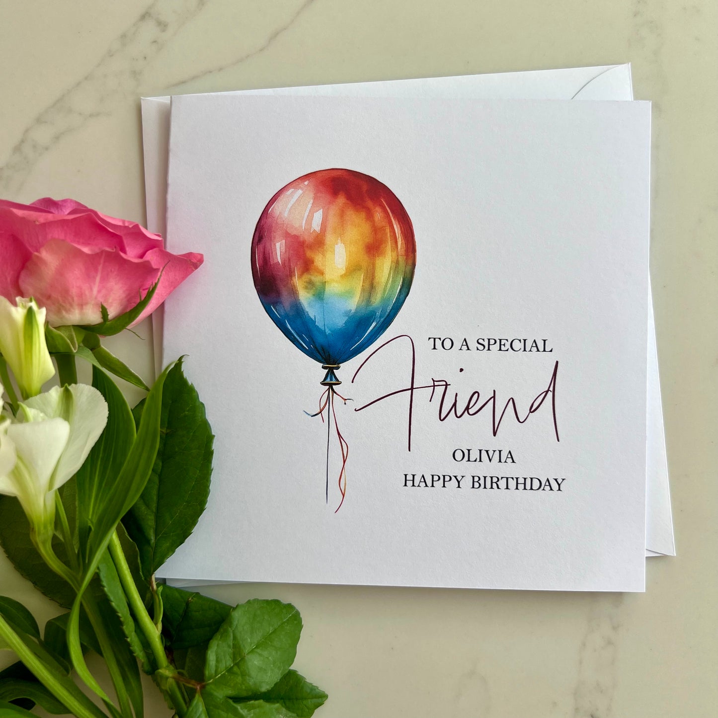 Personalised Greeting card with rainbow balloon illustration and flowers on a marble surface