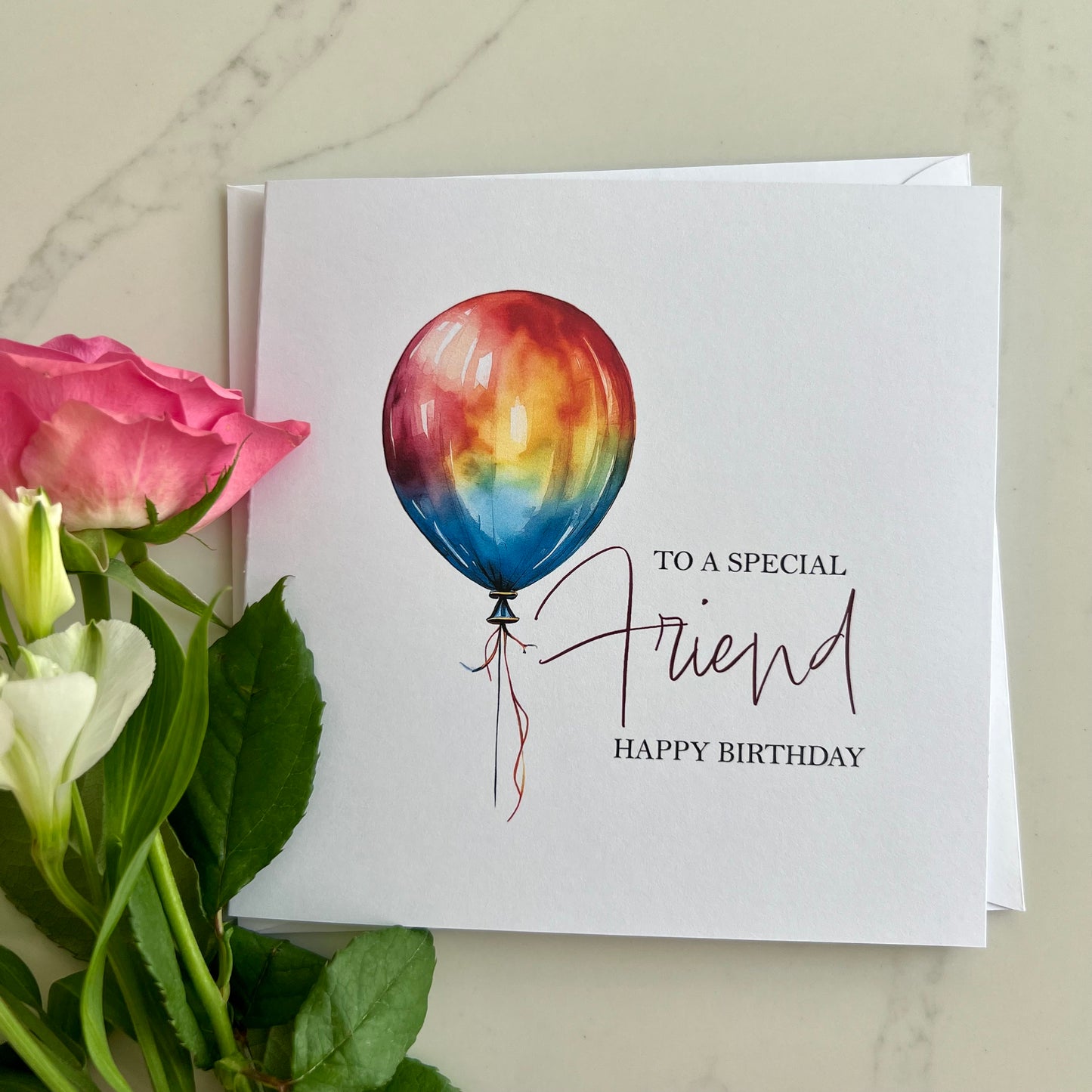 Personalised Greeting card with rainbow balloon illustration and flowers on a marble surface