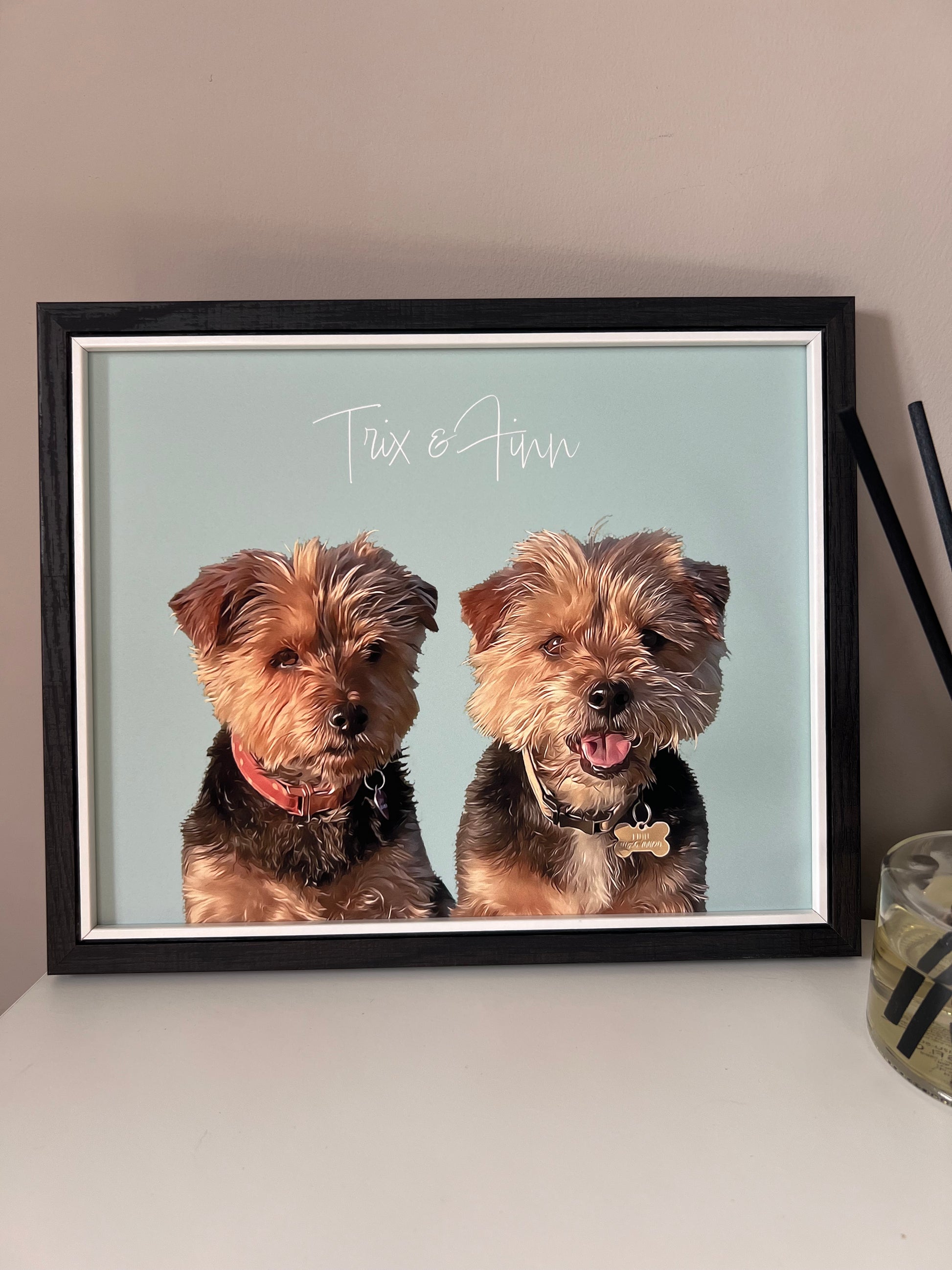 Framed print of a pet portrait of two Yorkshire terrier dogs with their names on a light blue background.