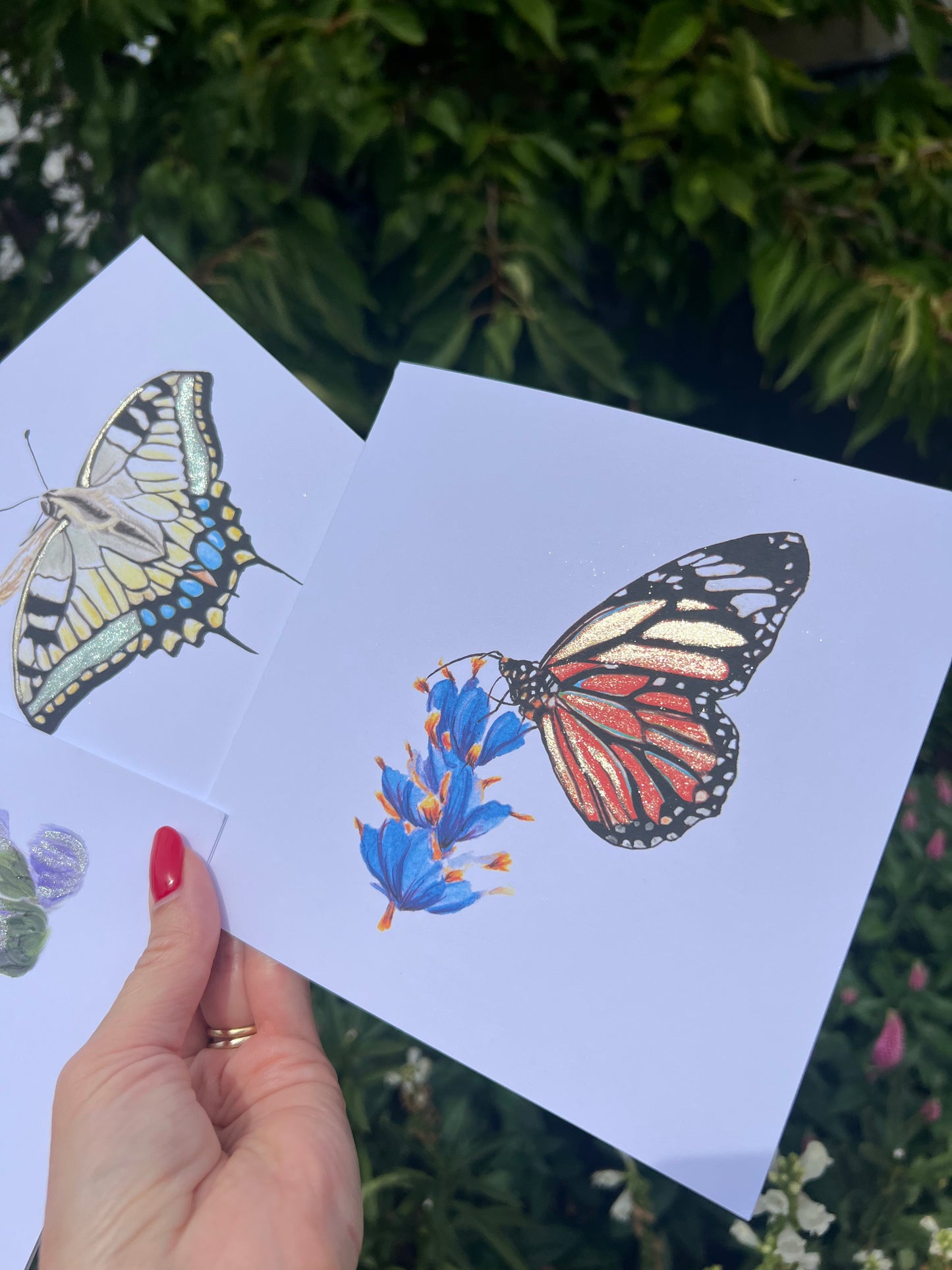 Hand holding a card with Monarch butterfly illustrations against a natural background with metallic gold accents.