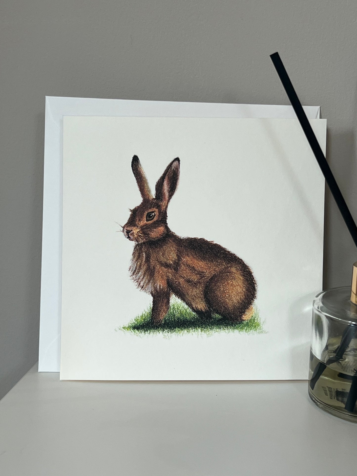 Handmade greeting card with artwork of a hare in warm browns and deep orange on an ivory background