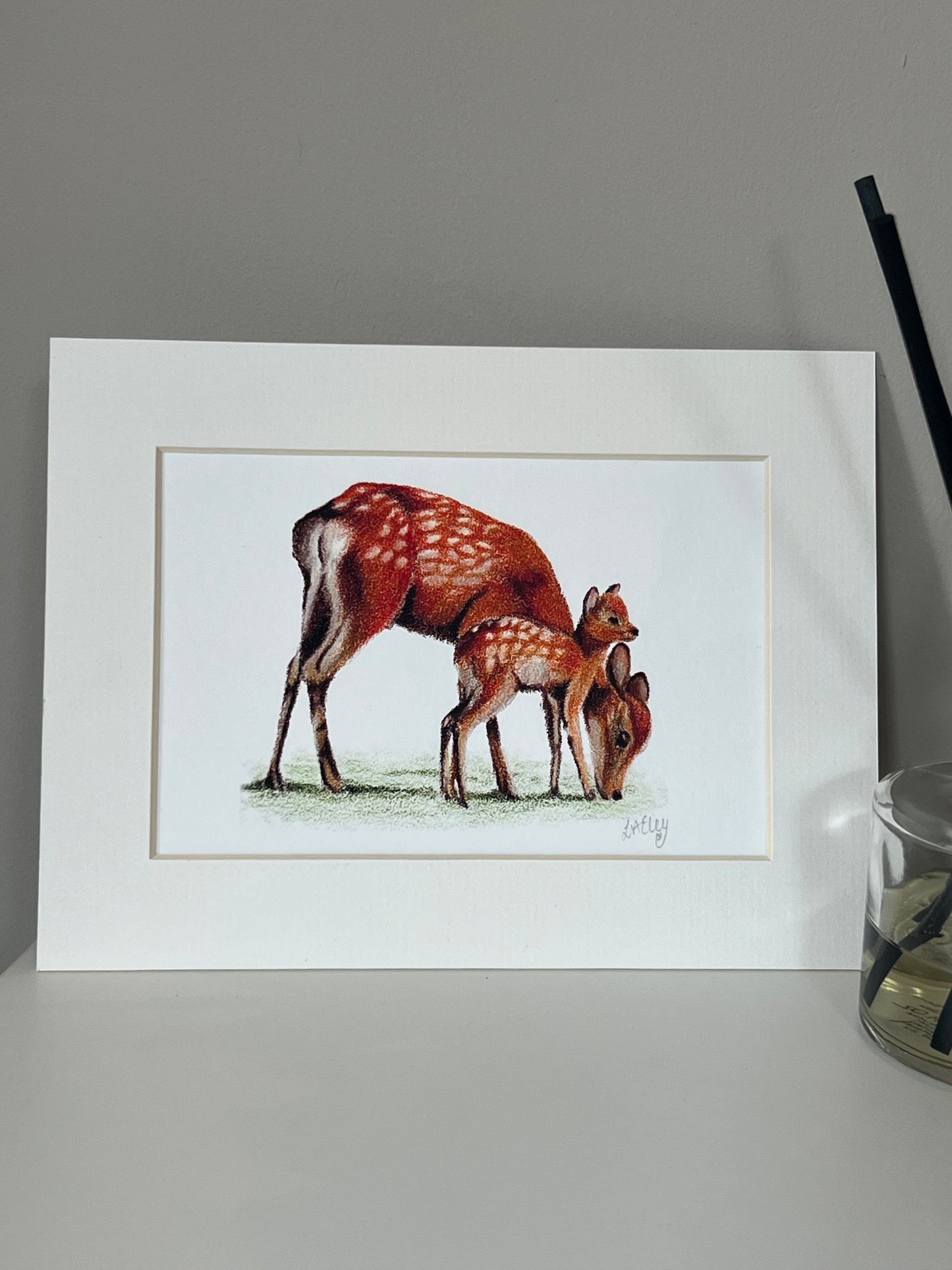 Artwork of a Sika Deer Mother and Fawn in vibrant oranges and reds on a white background in a white mount.