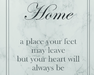 Close up of a print with the text 'Home a place your feet may leave, but your heart will always be' on a grey marble background, with a double border and white mount.