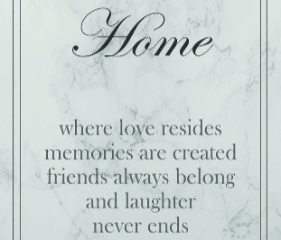 Close up of a framed print with the text 'Home - where love resides, memories are created, friends always belong, and laughter never ends' on a grey marble background.