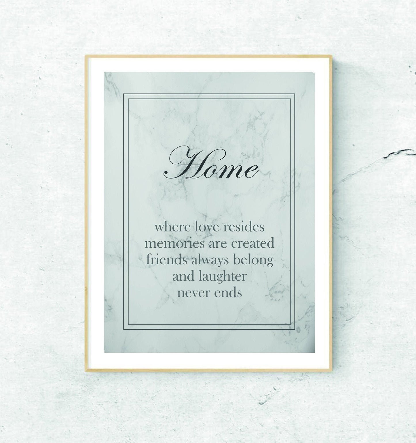 A framed print with the text 'Home - where love resides, memories are created, friends always belong, and laughter never ends' on a grey marble background.