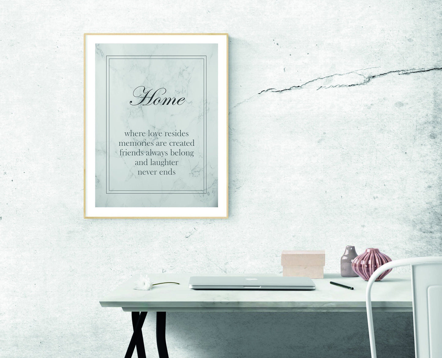 A framed print with the text 'Home - where love resides, memories are created, friends always belong, and laughter never ends' on a grey marble wall background.