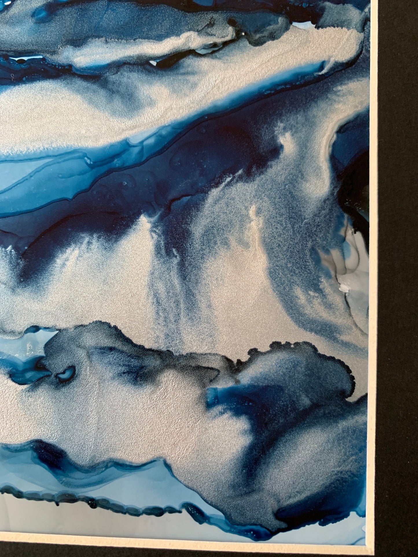 An abstract ink painting in shades of blue and silver, presented in a black mount.