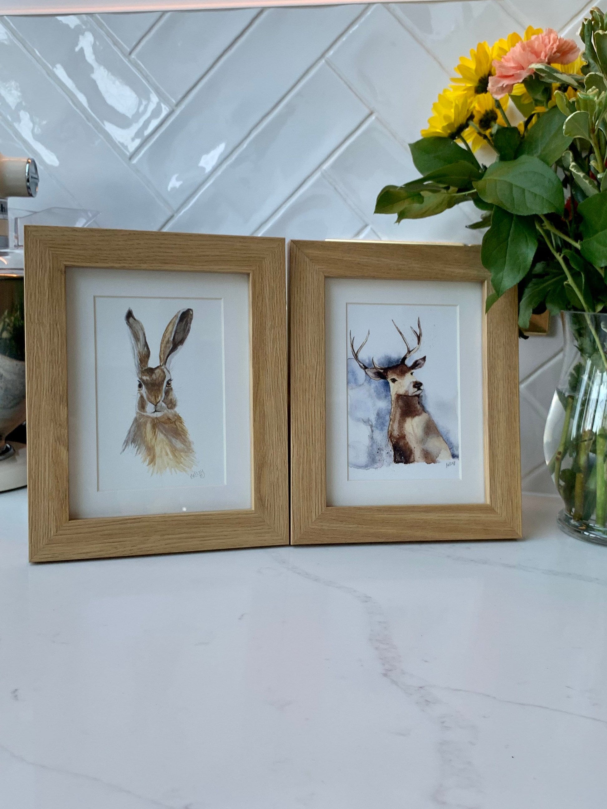 Watercolour stag in brown, grey and blue tones and Watercolour Hare in a white mount and wooden frame.