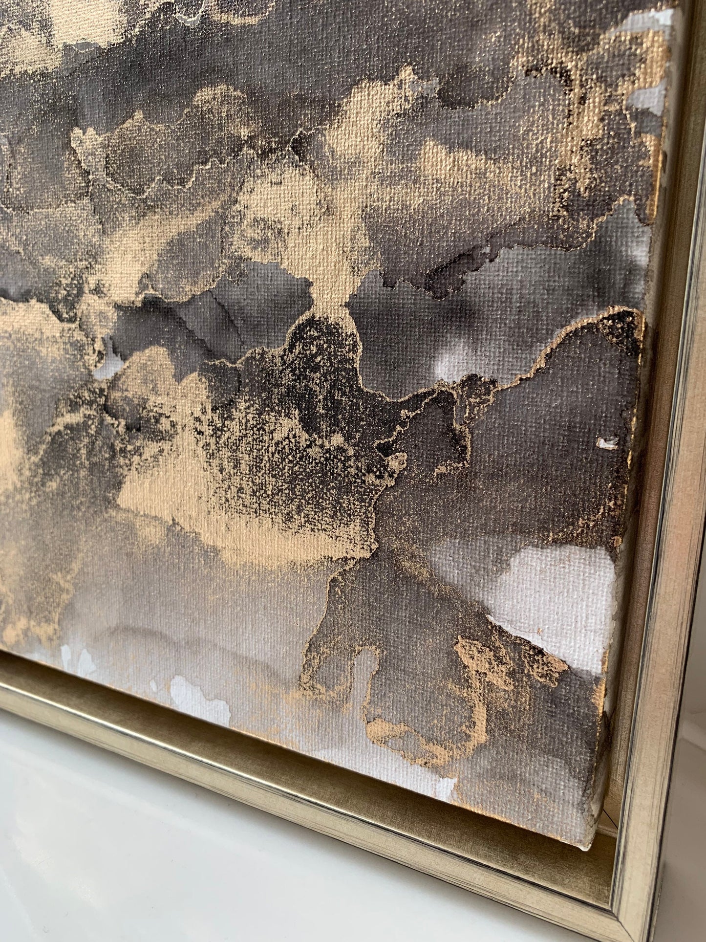 An abstract grey black and gold alcohol ink painting on canvas with a gold frame, displayed against a white background.