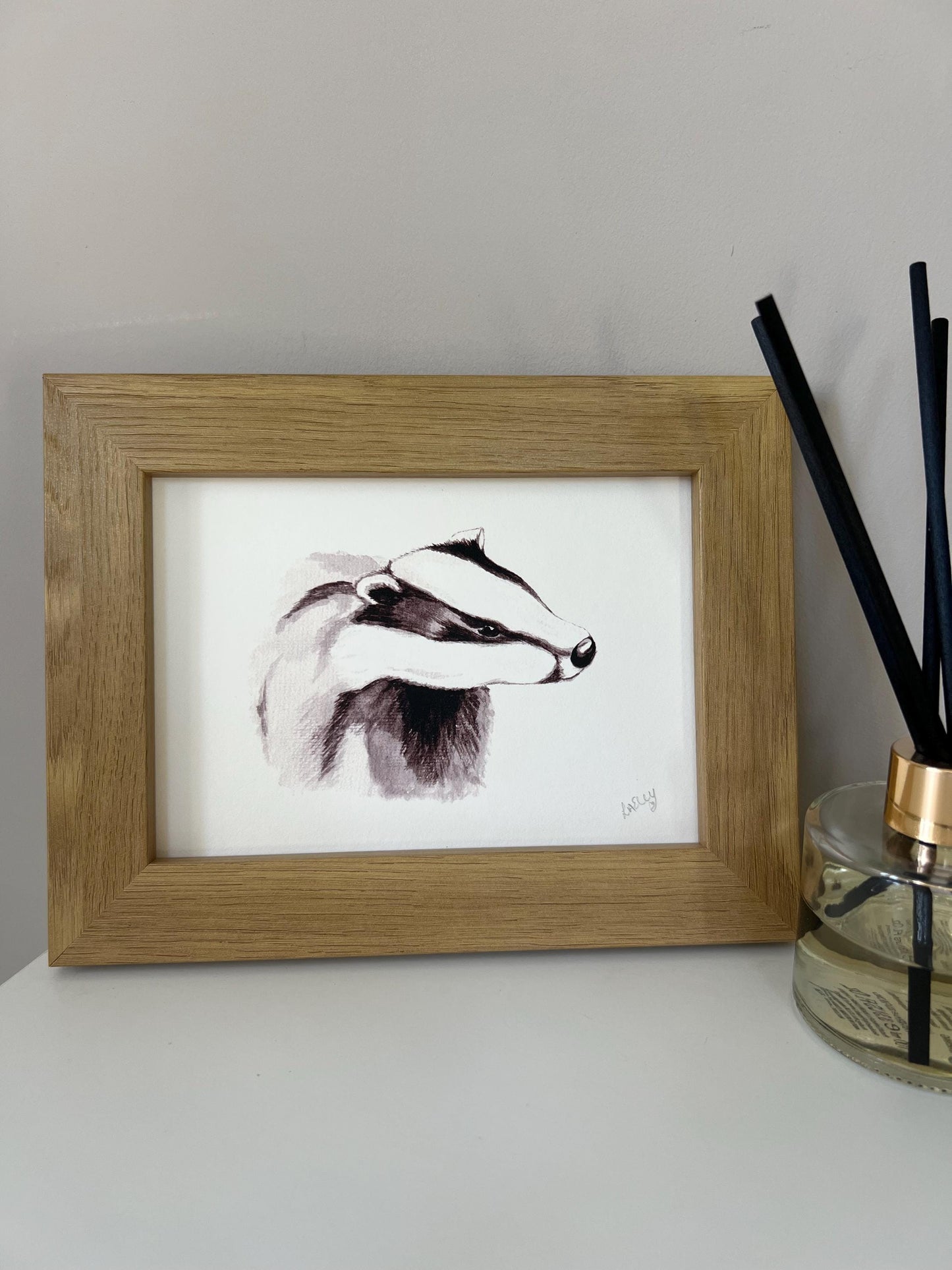 Watercolour young badger painting in grey tones in a oak finish wooden frame.