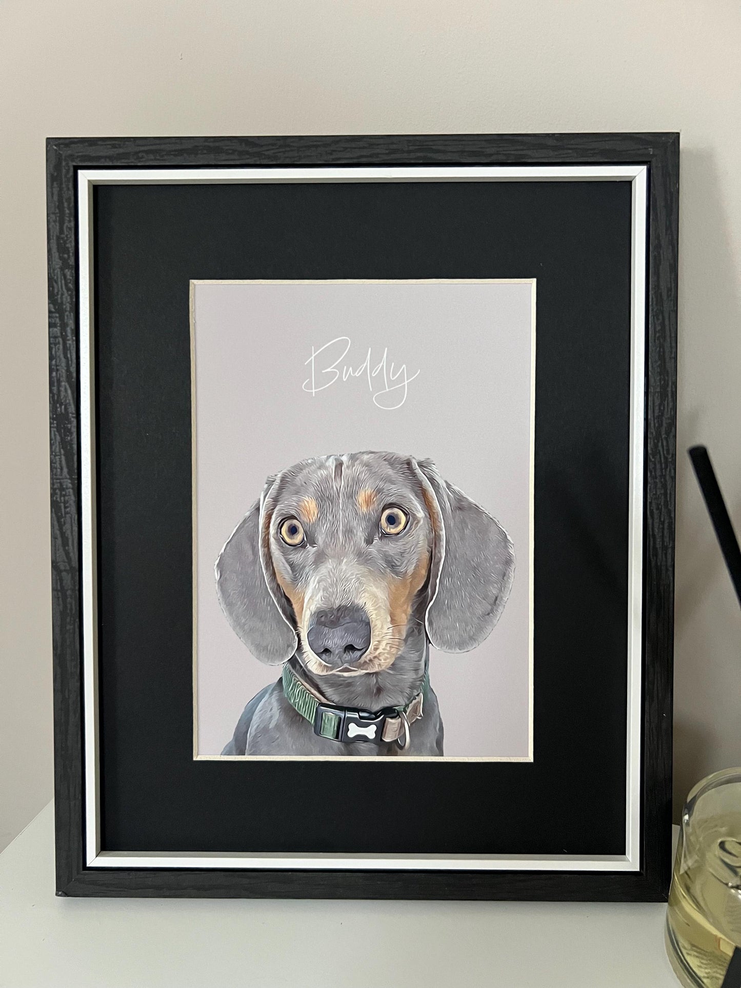 A custom digital pet portrait of a dachshund dog named Buddy, displayed in a wooden frame with black mount and grey background.