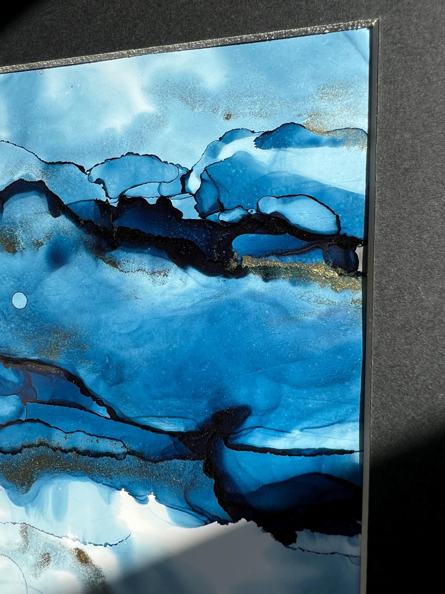 An A5 size contemporary ink painting featuring blue and metallic colors with gold shimmers, presented in a black frame.