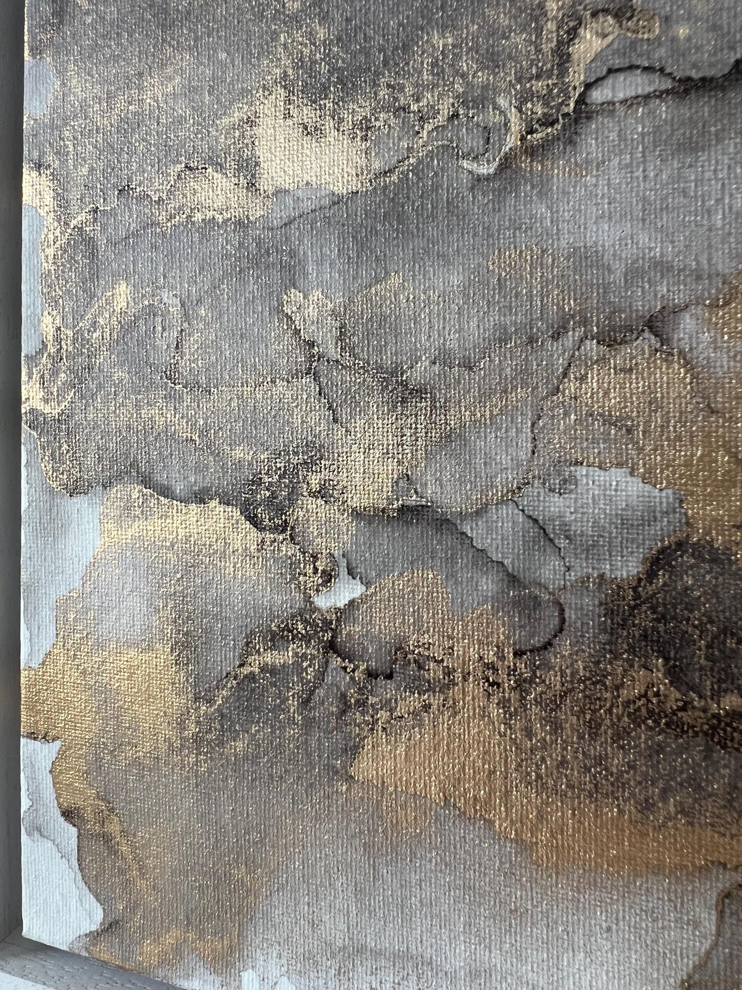 An abstract grey black and gold alcohol ink painting on canvas with a white frame.