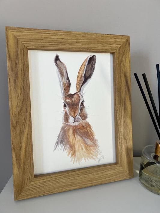 Watercolour hare in brown and grey tones in a oak finish wooden frame.