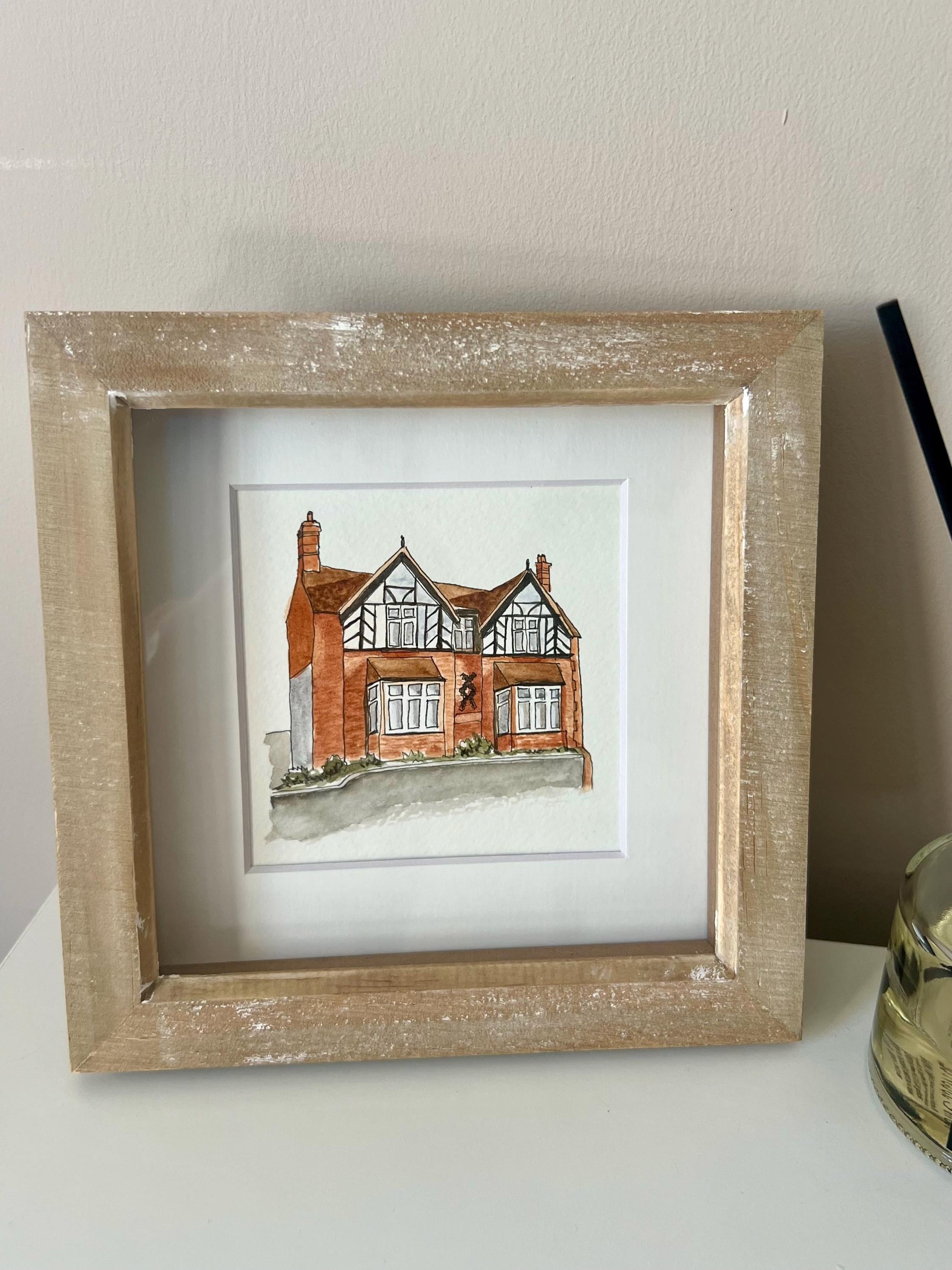 A custom watercolour portrait of a house, hand-painted and displayed in a wooden frame.