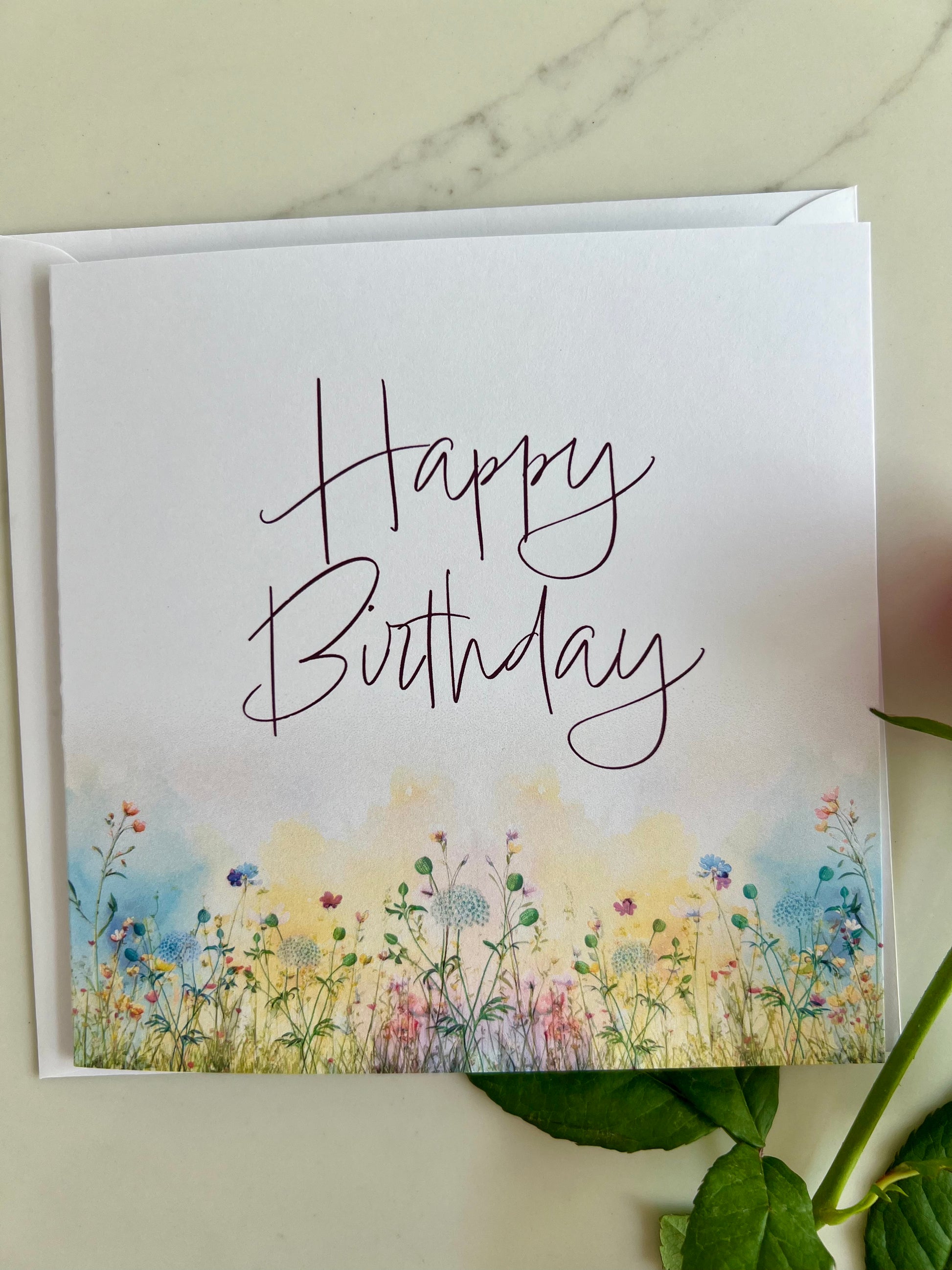 Birthday card with 'Happy Birthday' text and floral design on a marble surface.