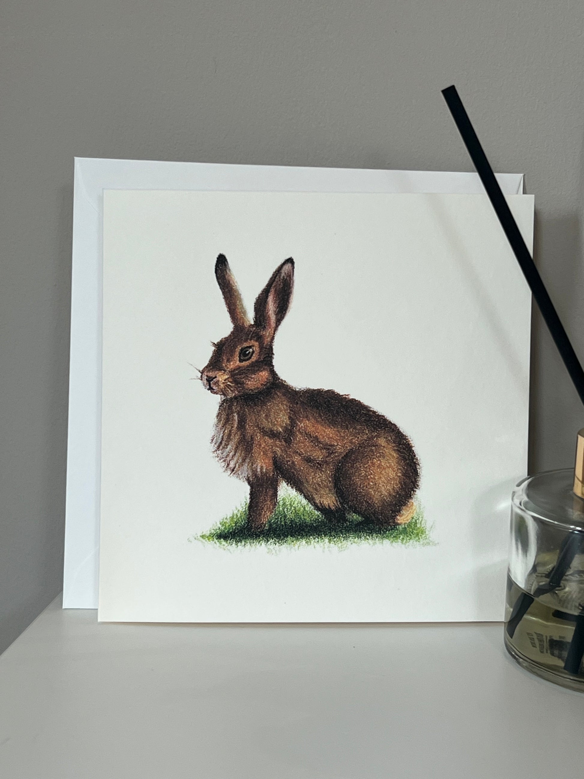 Handmade greeting card with artwork of a hare in warm browns and deep orange on an ivory background 