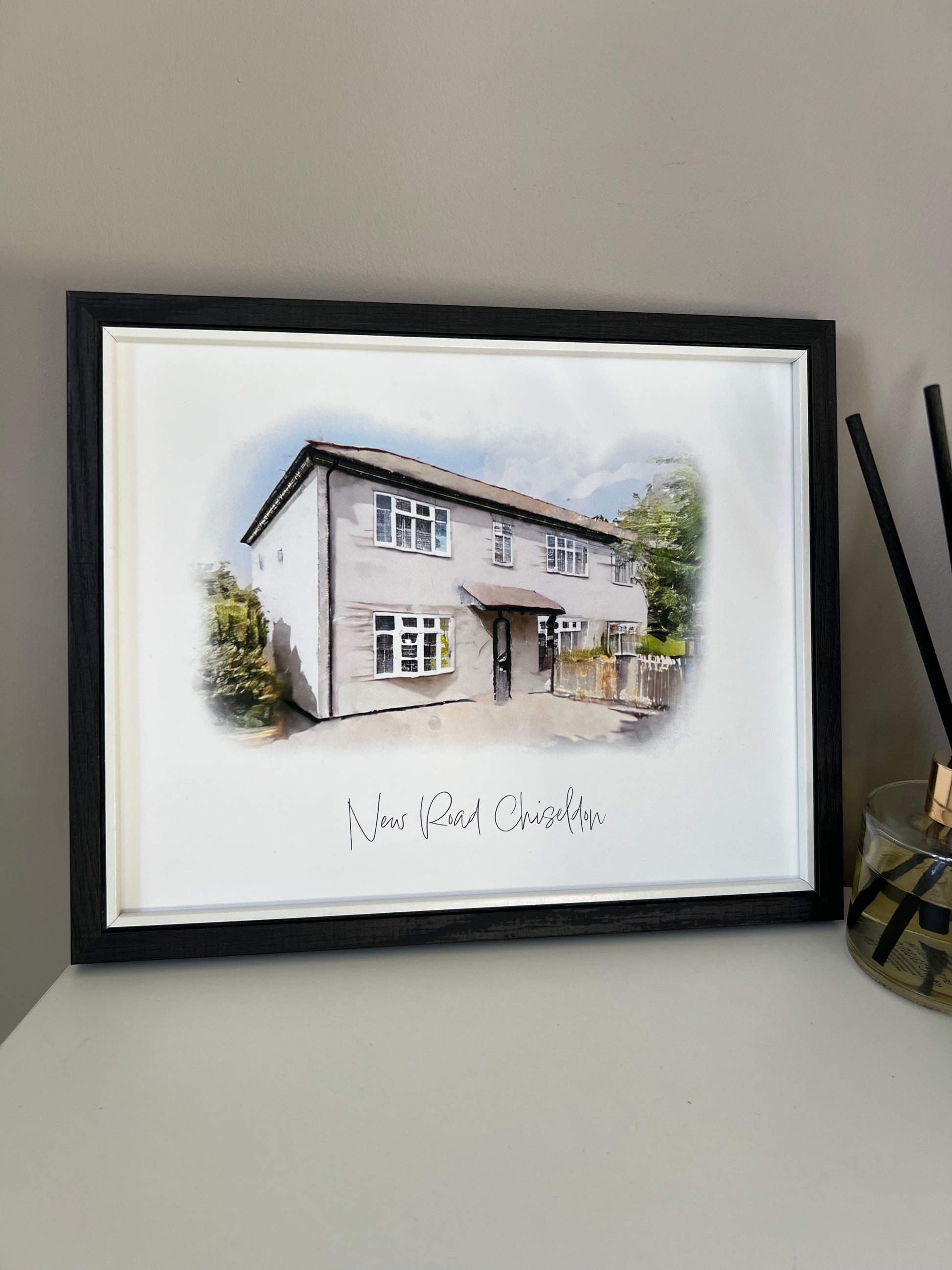 Framed artwork of a cottage house portrait in digital watercolour in a black frame. 