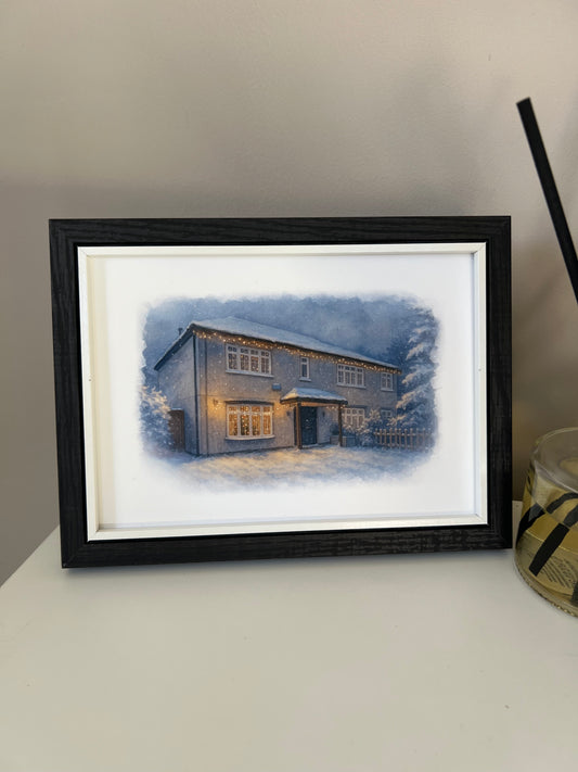 Framed artwork of a cottage style  house portrait in a winter snowy scene  in digital watercolour in a black finish frame.