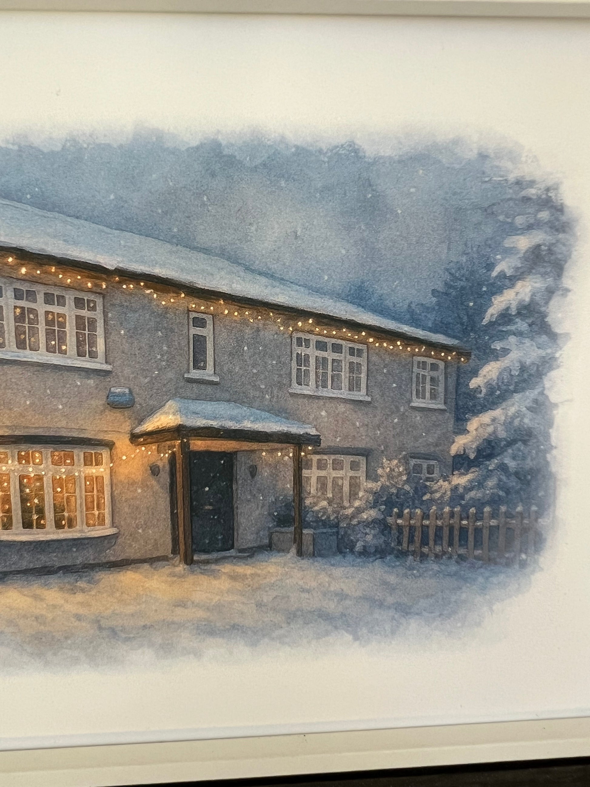 Close up of the right side of a framed artwork of a cottage style  house portrait in a winter snowy scene  in digital watercolour in a black finish frame.