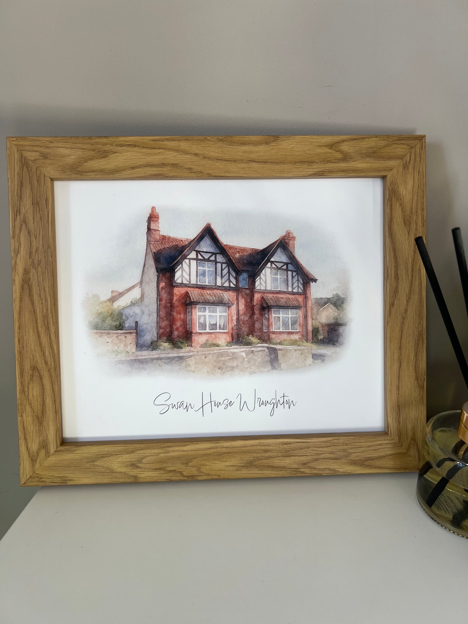 Framed artwork of a tudor style period house portrait in digital watercolour in an oak finish frame.