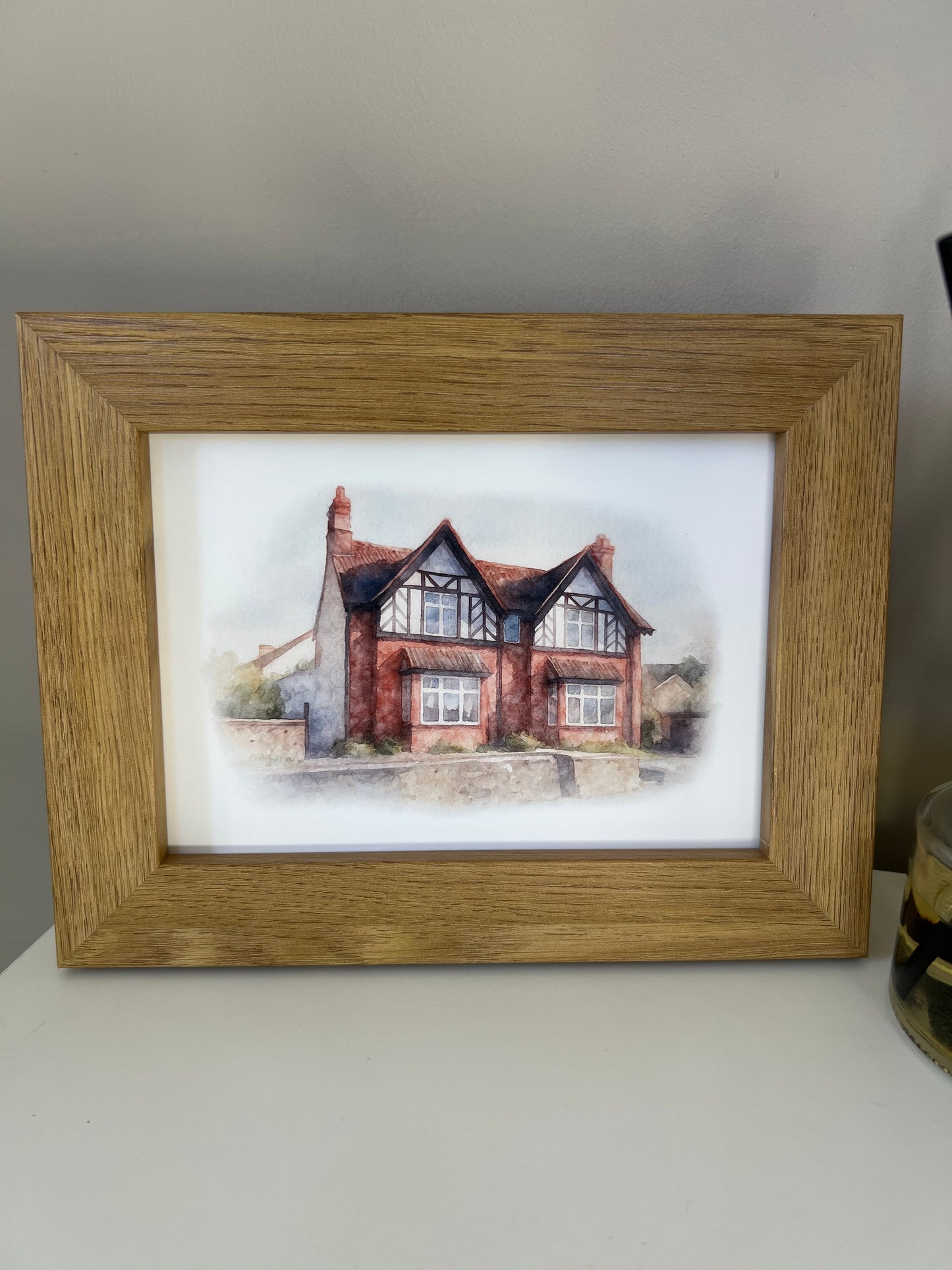 Framed artwork of a tudor style period house portrait in digital watercolour in an oak finish frame.