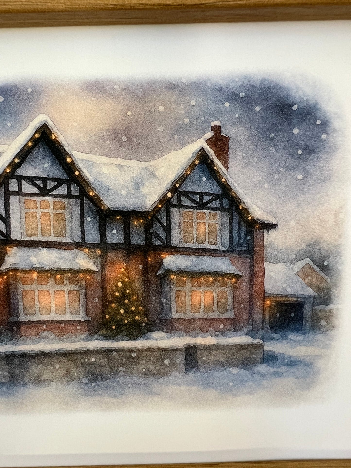 Close up of right side of a framed artwork of a Tudor style period house portrait in a winter snowy scene  in digital watercolour in an oak finish frame.