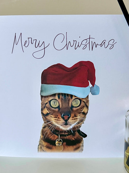 Close up of a custom Christmas Card of a Bengal Cat wearing a Santa hat with the words "Merry Christmas".