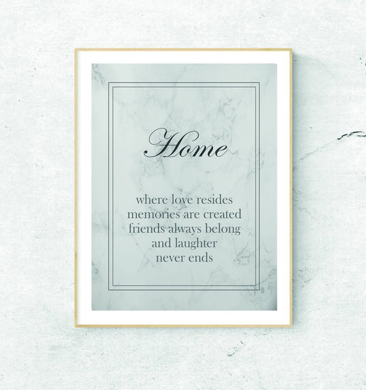 A framed print with the text 'Home - where love resides, memories are created, friends always belong, and laughter never ends' on a grey marble background.