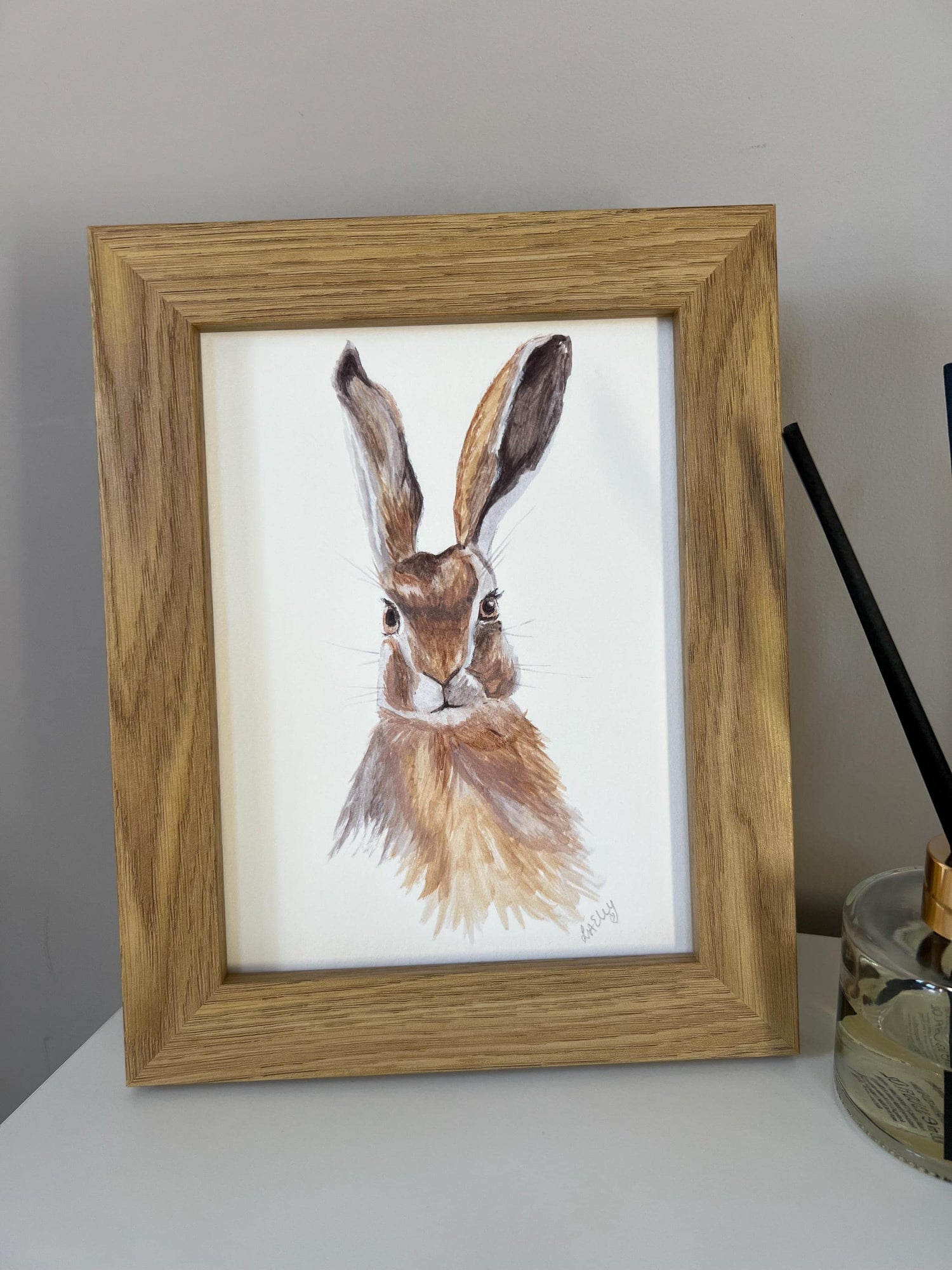 Watercolour hare in brown and grey tones in a wooden frame.