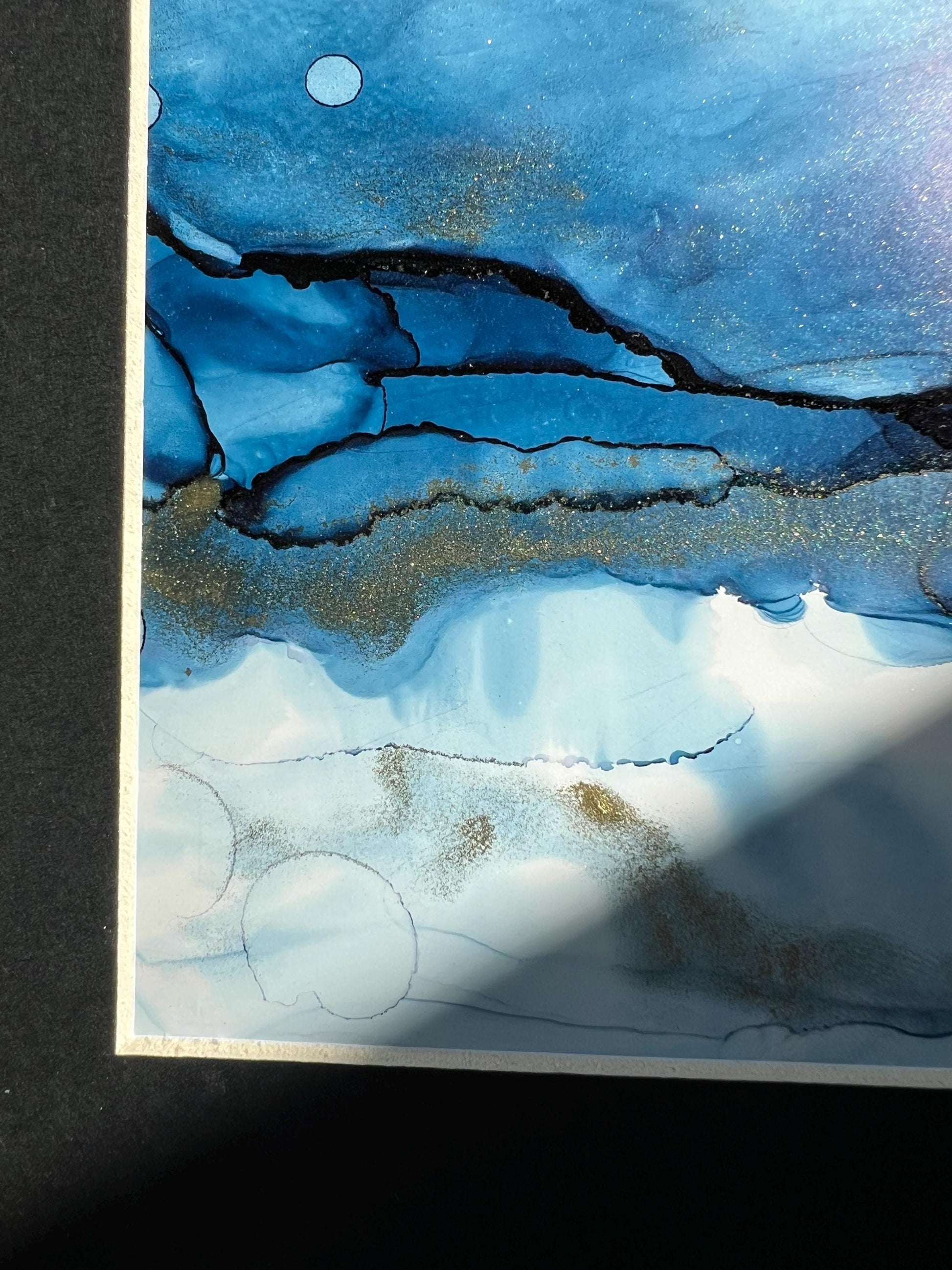 An A5 size contemporary ink painting featuring blue and metallic colors with gold shimmers, presented in a black frame.