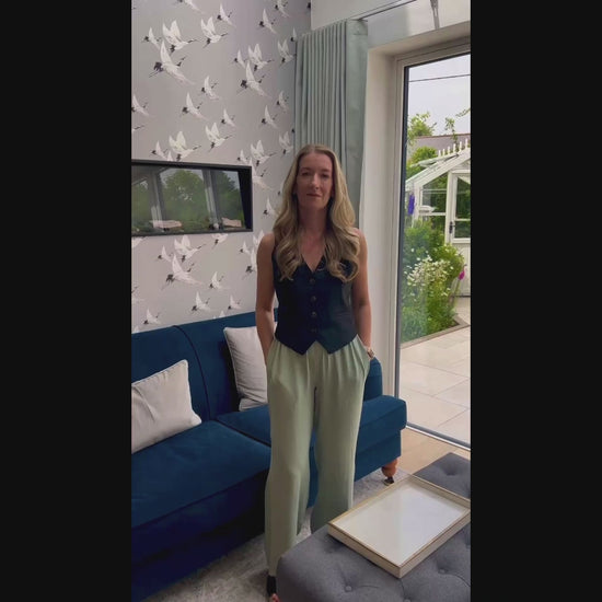 Video of artist with artwork of a custom watercolour house portrait and original photo in kitchen with garden in the background. 