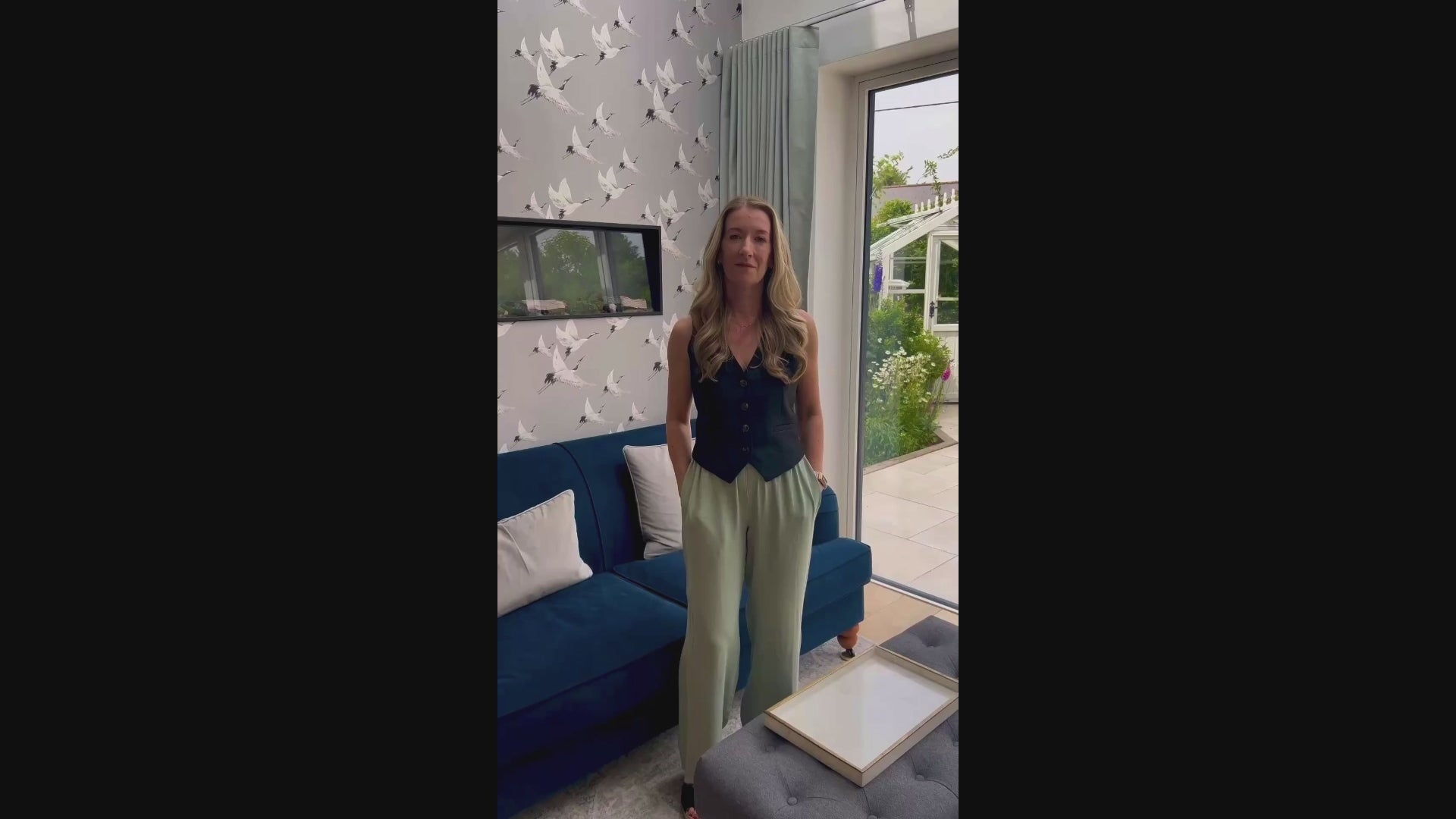 Video of artist with artwork of a custom watercolour house portrait and original photo in kitchen with garden in the background. 