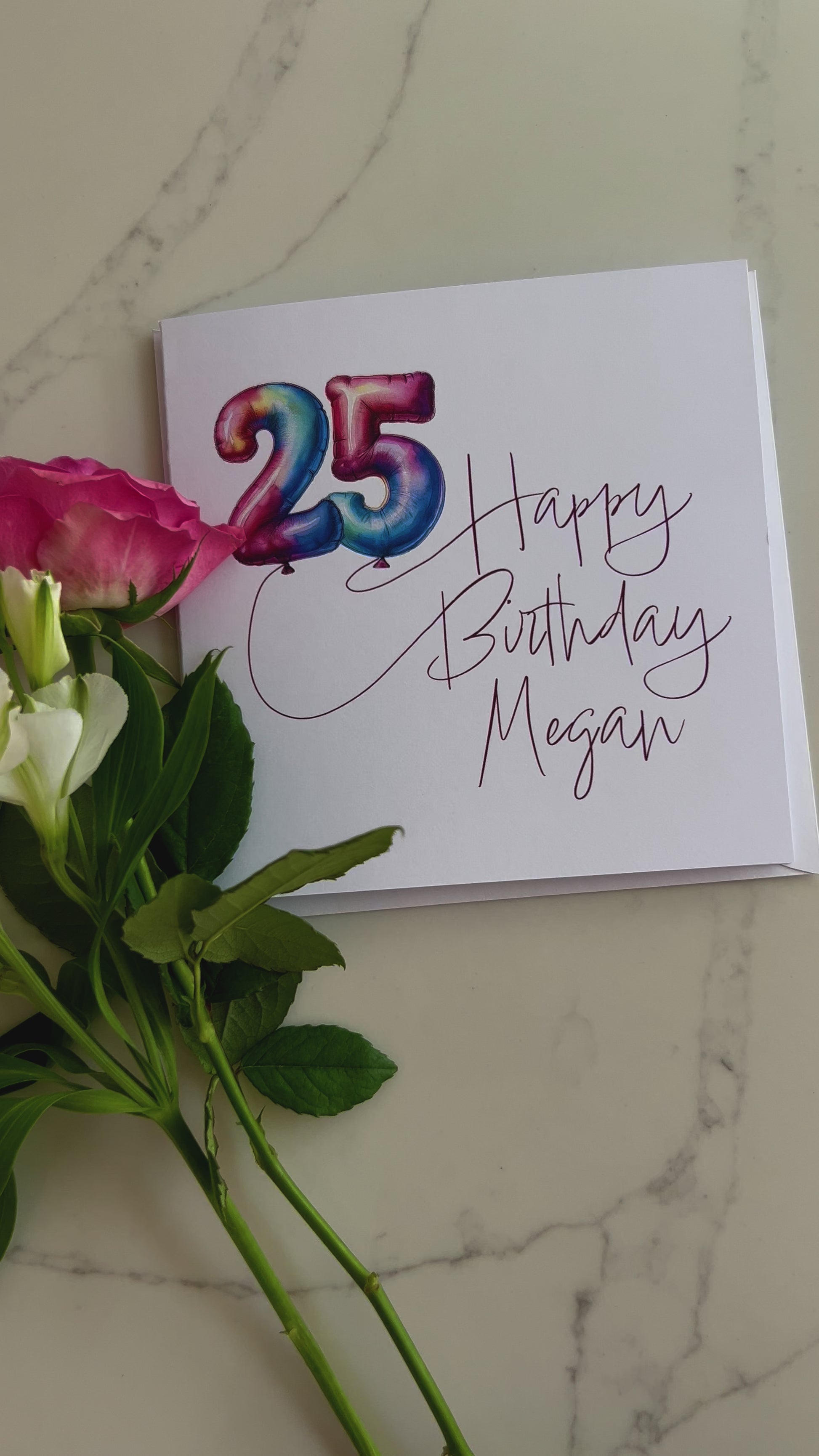 Video of a Personalised Birthday card with colourful '25' in balloons and 'Happy Birthday' text, surrounded by flowers on a marble surface.